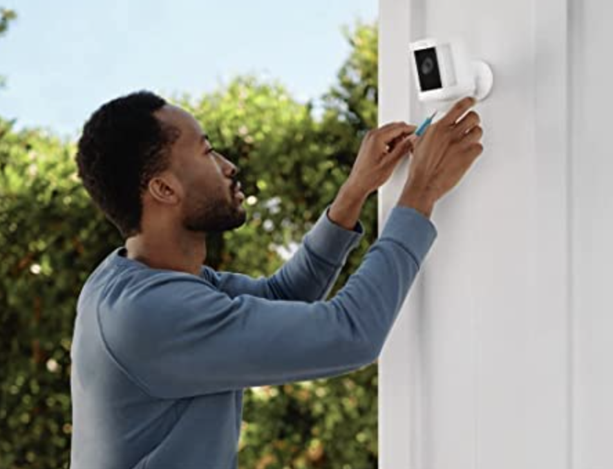 Man installing Ring Spotlight Cam Plus on exterior wall